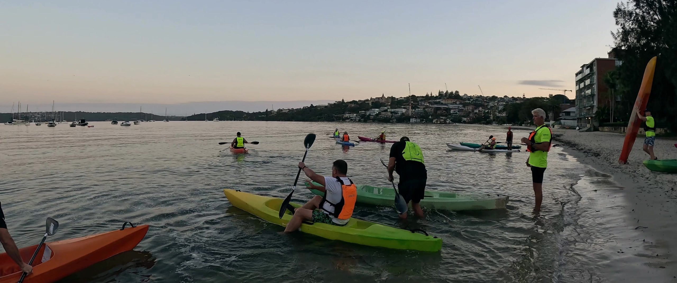 A group launching colourful kayaks into Rose Bay