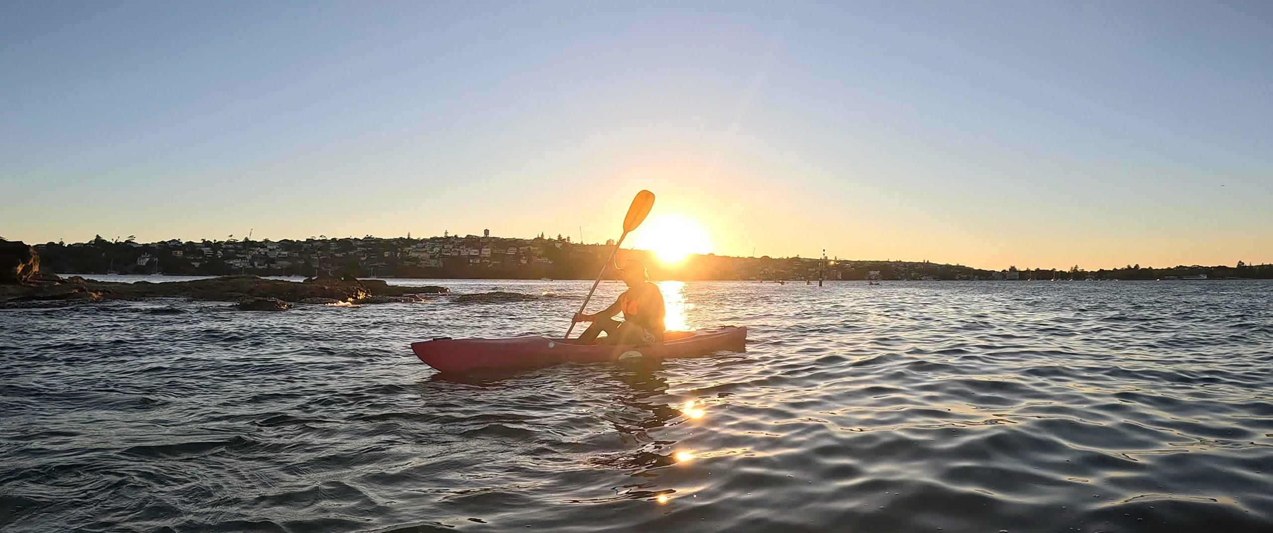 A kayaker moving through golden sunrise light